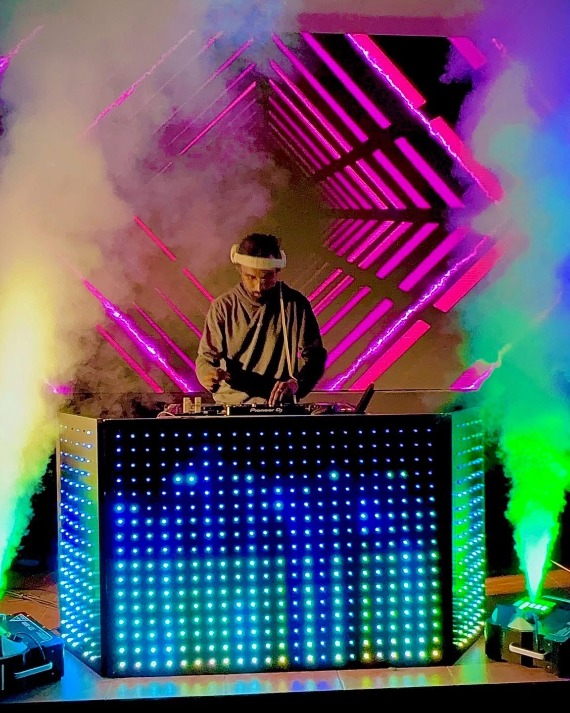 DJ performing under neon lights with fog